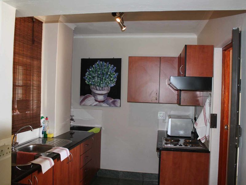 Compact kitchen featuring dark laminate cabinetry, granite countertops, a stainless steel sink, and a built-in electric hob with an extractor fan.