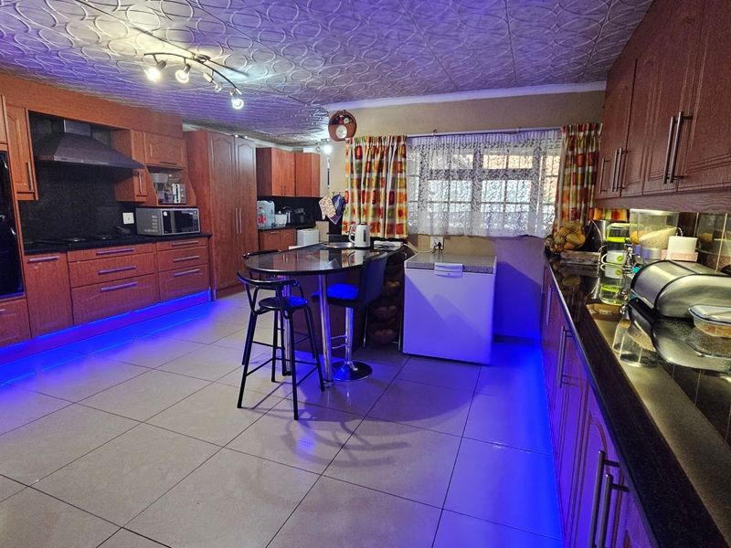 Spacious kitchen featuring extensive wooden cabinetry, granite countertops, tiled flooring, and a textured ceiling with integrated lighting.