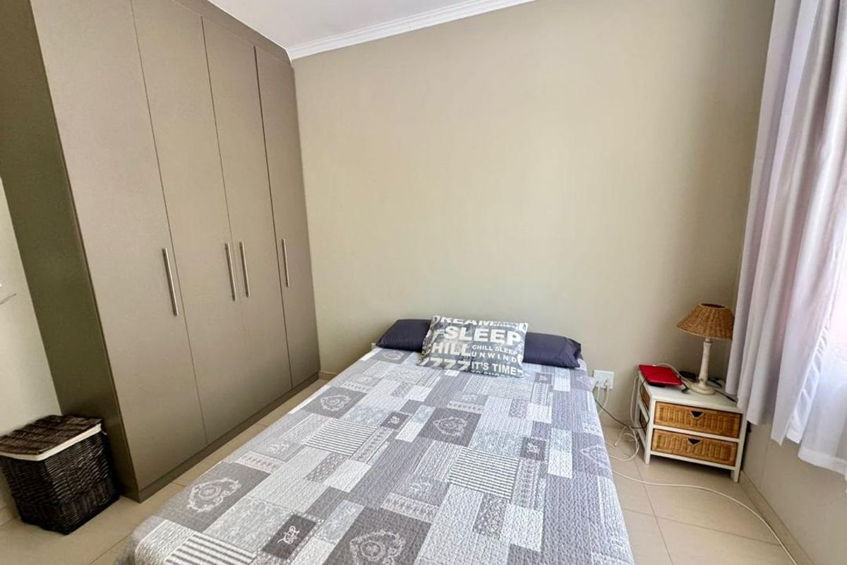 A well-maintained bedroom featuring neutral wall tones, tiled flooring, and floor-to-ceiling built-in cupboards providing ample storage space.