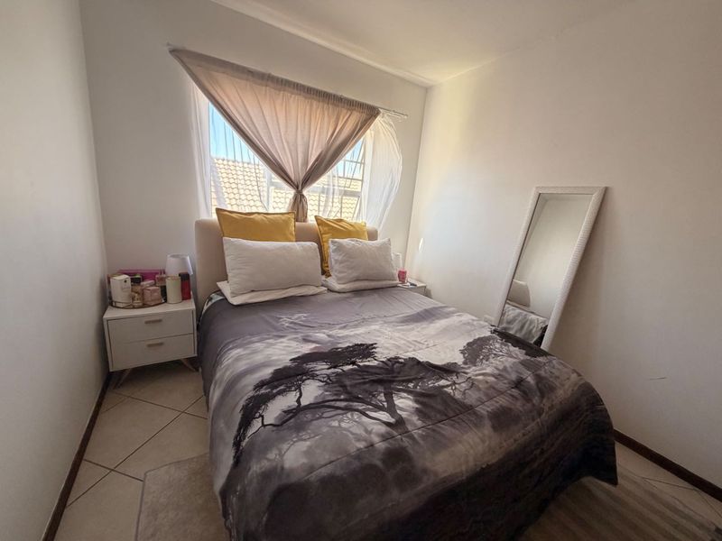 A cozy bedroom featuring tiled flooring and a window, providing a functional and comfortable living space.