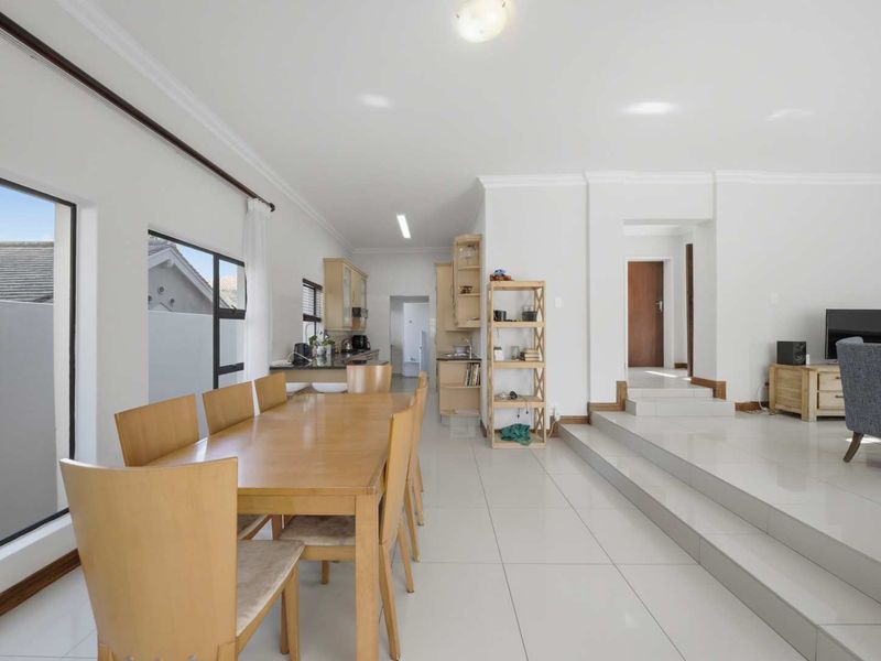 Spacious open-plan living and dining area featuring tiled floors, a raised living platform, and a functional kitchen with built-in cabinetry.