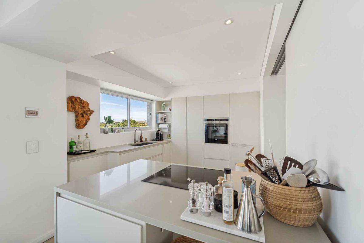 Modern kitchen featuring a central island with induction hob, sleek handleless cabinetry, stone countertops, and integrated oven, finished with high-quality fixtures.