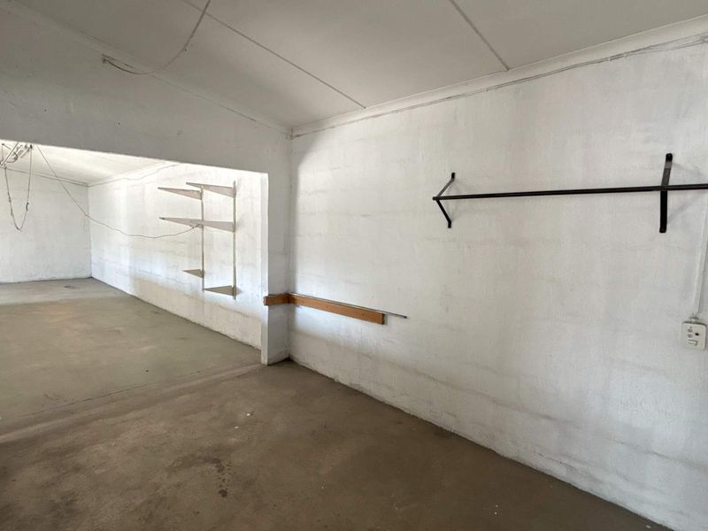 An open-plan industrial utility space featuring concrete flooring, painted masonry walls, and basic wall-mounted storage fixtures.