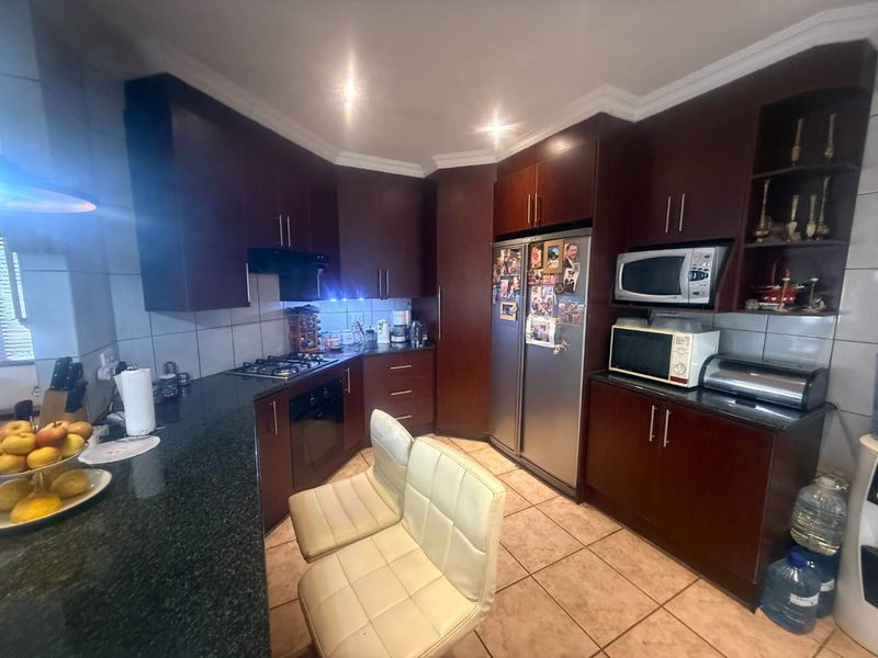 A functional kitchen featuring dark wood cabinetry, granite countertops, built-in oven, gas hob, and tiled flooring, offering a classic and practical workspace.