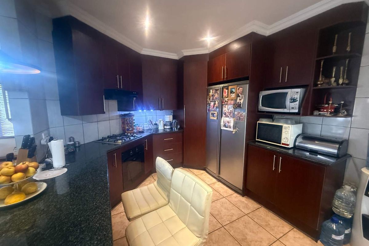 A functional kitchen featuring dark wood cabinetry, granite countertops, built-in oven, gas hob, and tiled flooring, offering a classic and practical workspace.