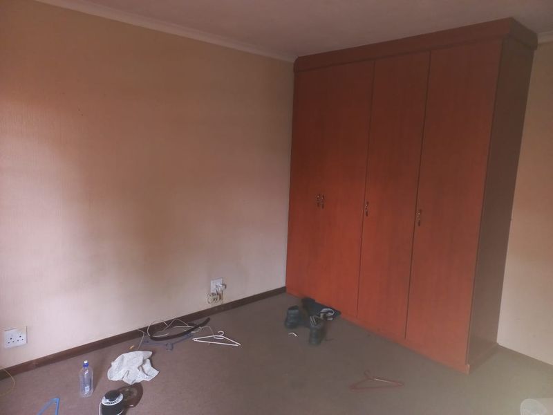 A bedroom featuring a large built-in wooden wardrobe and carpeted flooring, offering a blank canvas for potential interior updates.
