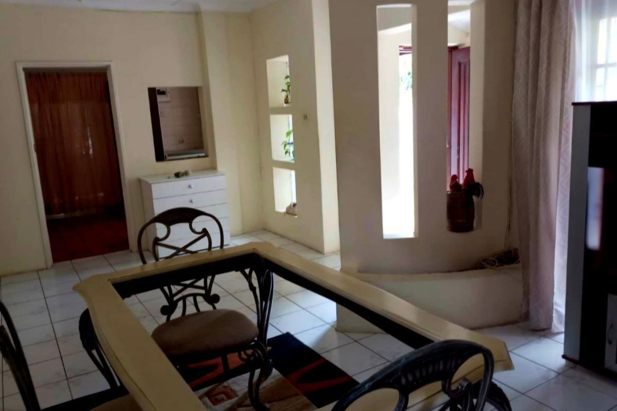 A living area featuring tiled flooring and decorative wall cutouts, providing a dated but functional space with potential for modern updates.