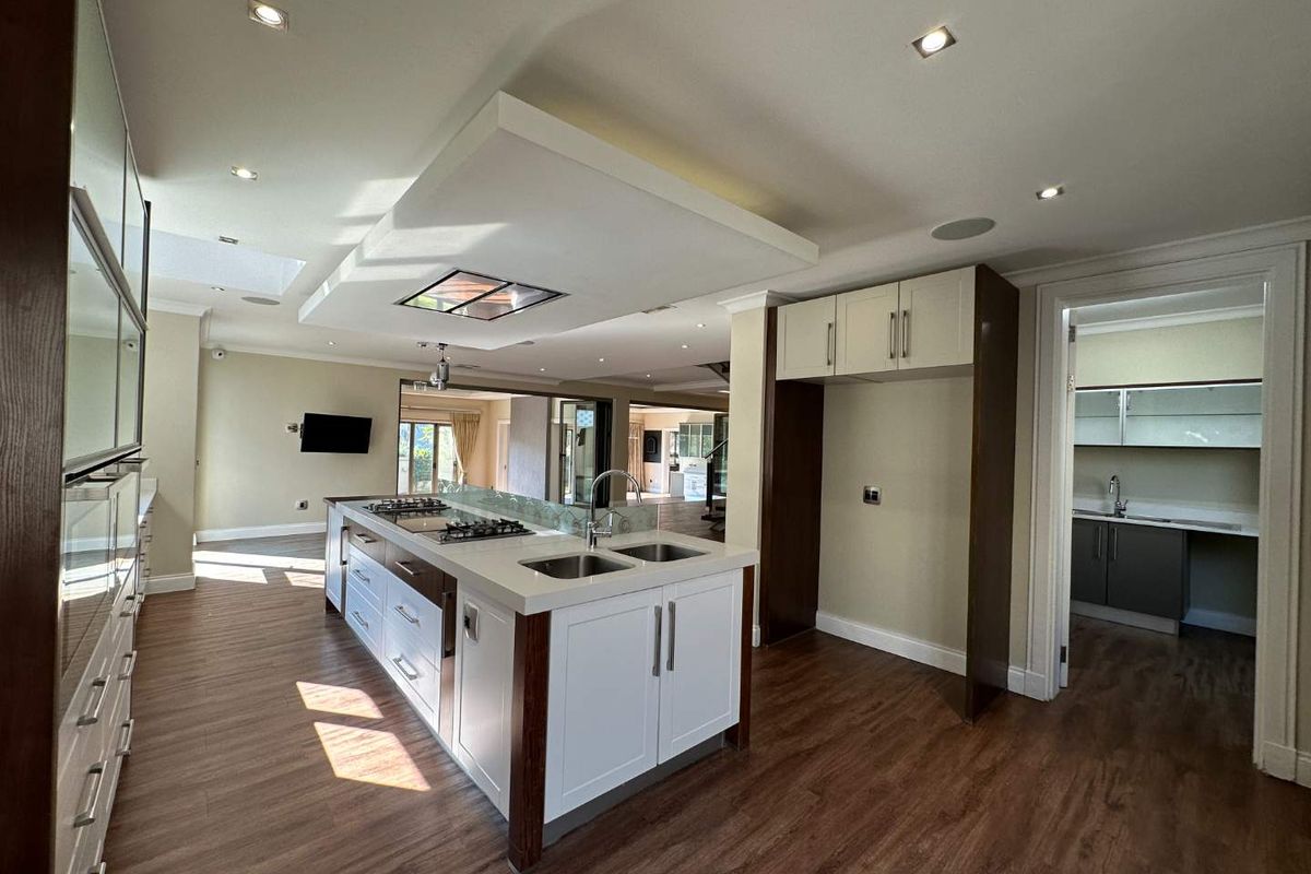 Spacious modern kitchen featuring a large central island with integrated gas hob and double sink, complemented by ample cabinetry and recessed ceiling lighting.
