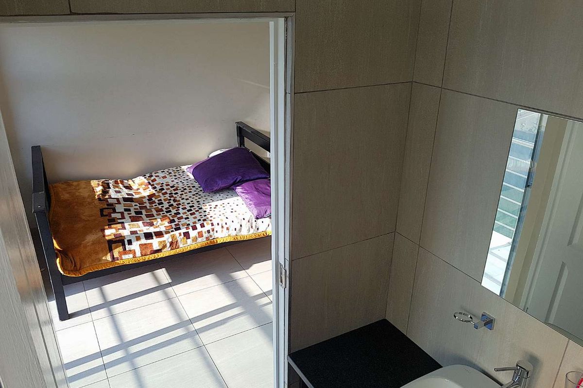 A view from a tiled bathroom looking into an adjacent bedroom space.