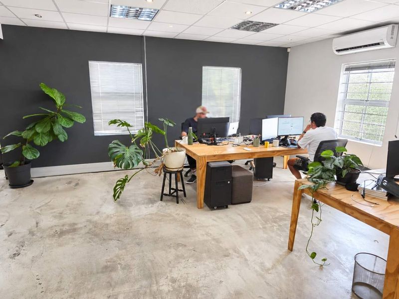 Open-plan office space featuring polished concrete floors, suspended ceilings with recessed lighting, and wall-mounted air conditioning.