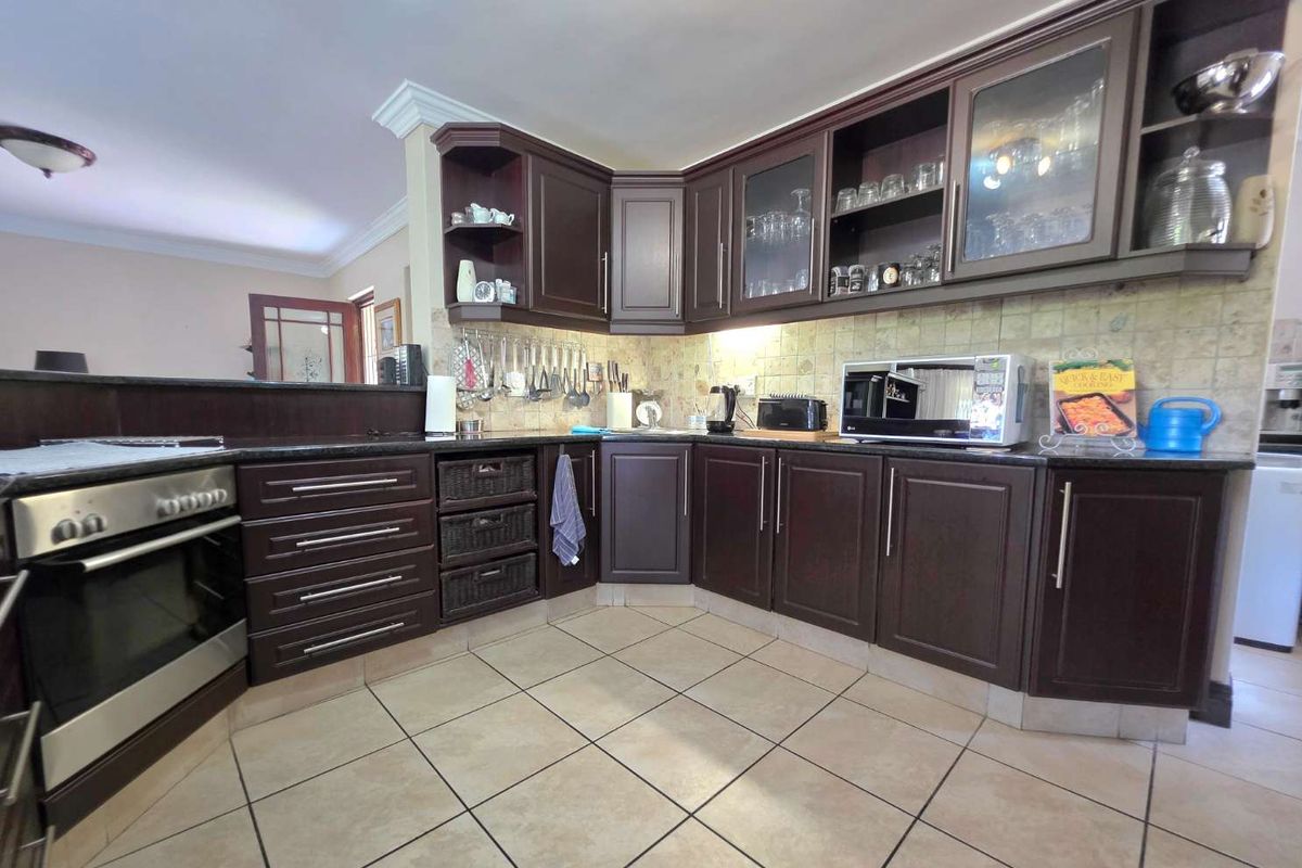 A functional kitchen featuring dark wood cabinetry, granite countertops, tiled flooring, and a built-in oven with a stainless steel finish.