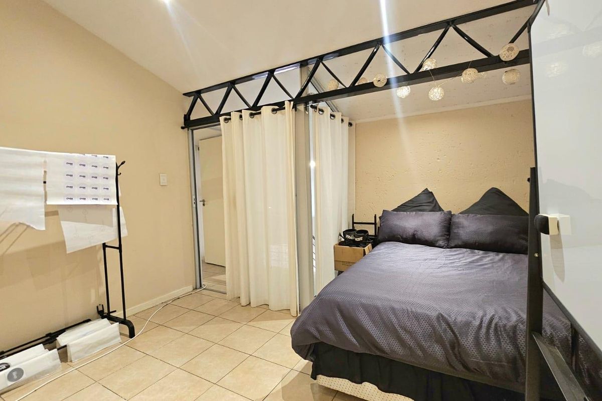 A bedroom featuring tiled flooring and a distinctive exposed black metal truss ceiling detail, providing a unique industrial aesthetic.