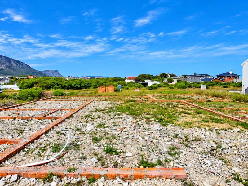 Vacant residential land featuring established brick foundation footings and visible plumbing connections, set against a scenic mountain backdrop in a developed neighborhood.