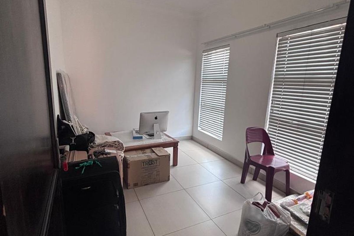 A functional bedroom or office space featuring neutral floor tiles, white walls, and fitted window blinds, offering a clean and versatile layout.