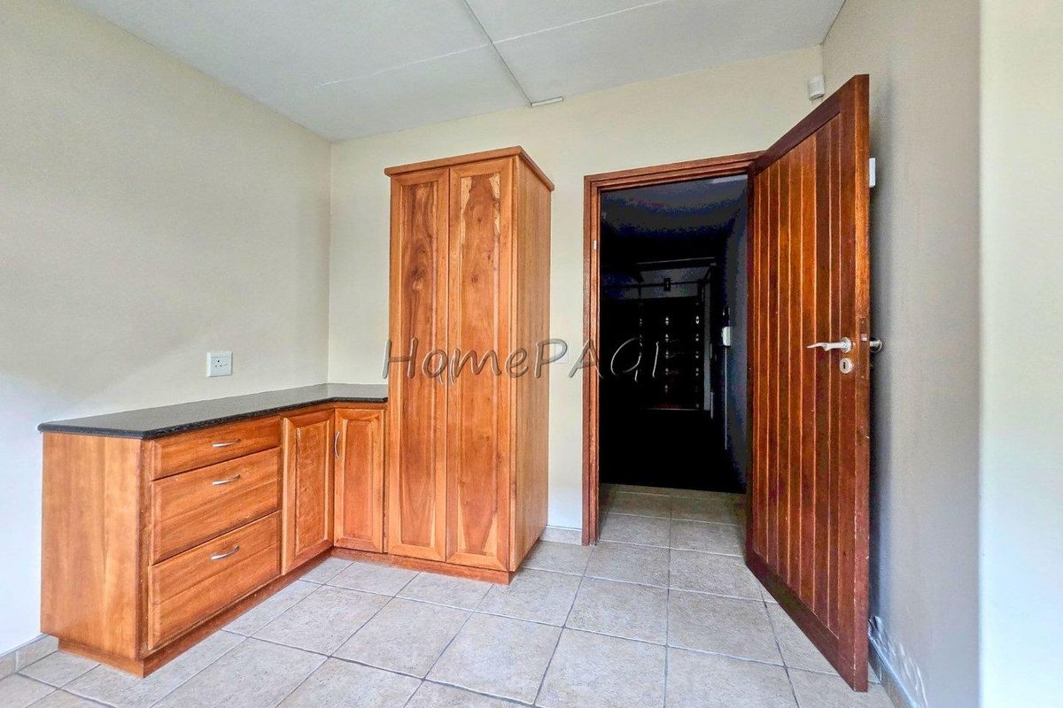 A bedroom featuring built-in wooden cabinetry with a granite countertop, tiled flooring, and a solid wooden door.