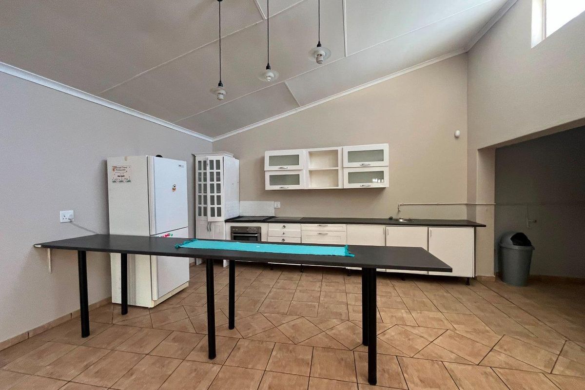 A functional kitchen featuring tiled flooring, built-in cabinetry, a built-in oven, and a vaulted ceiling with pendant lighting.