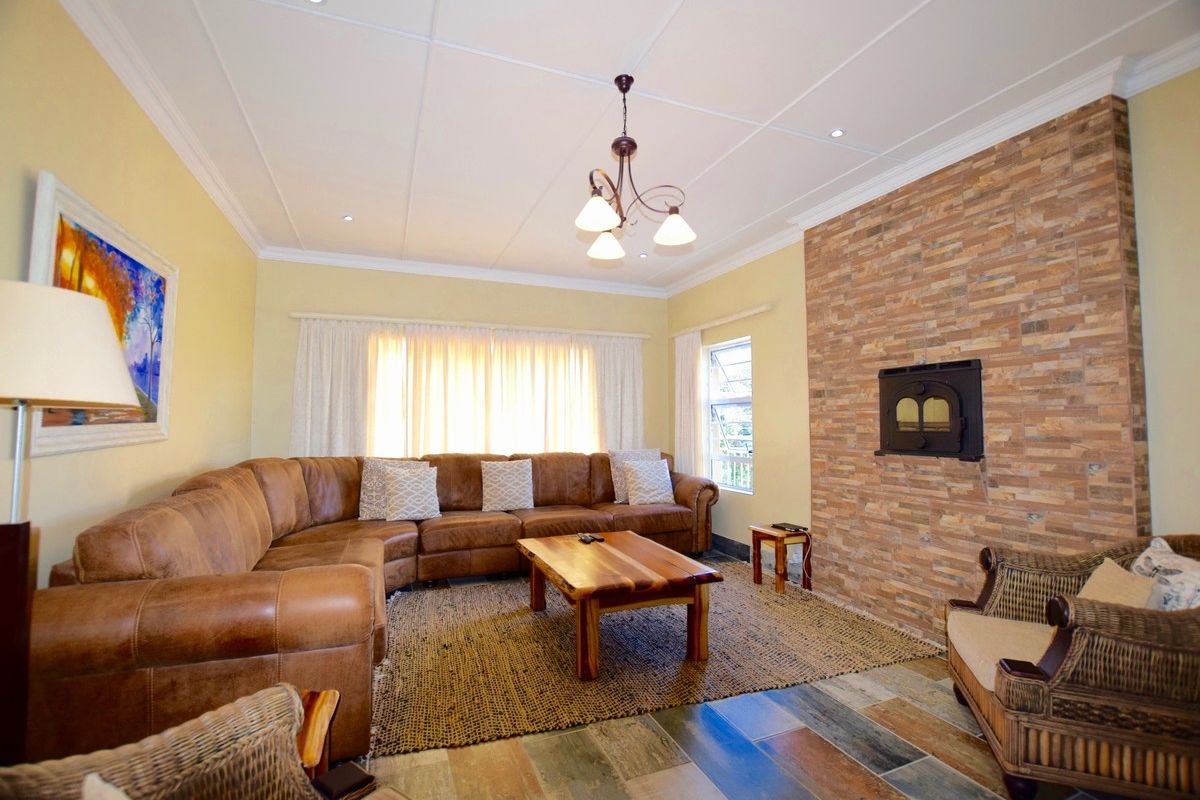 A comfortable living room featuring a prominent stone-clad fireplace, tiled flooring, and a coffered ceiling with a central light fixture.