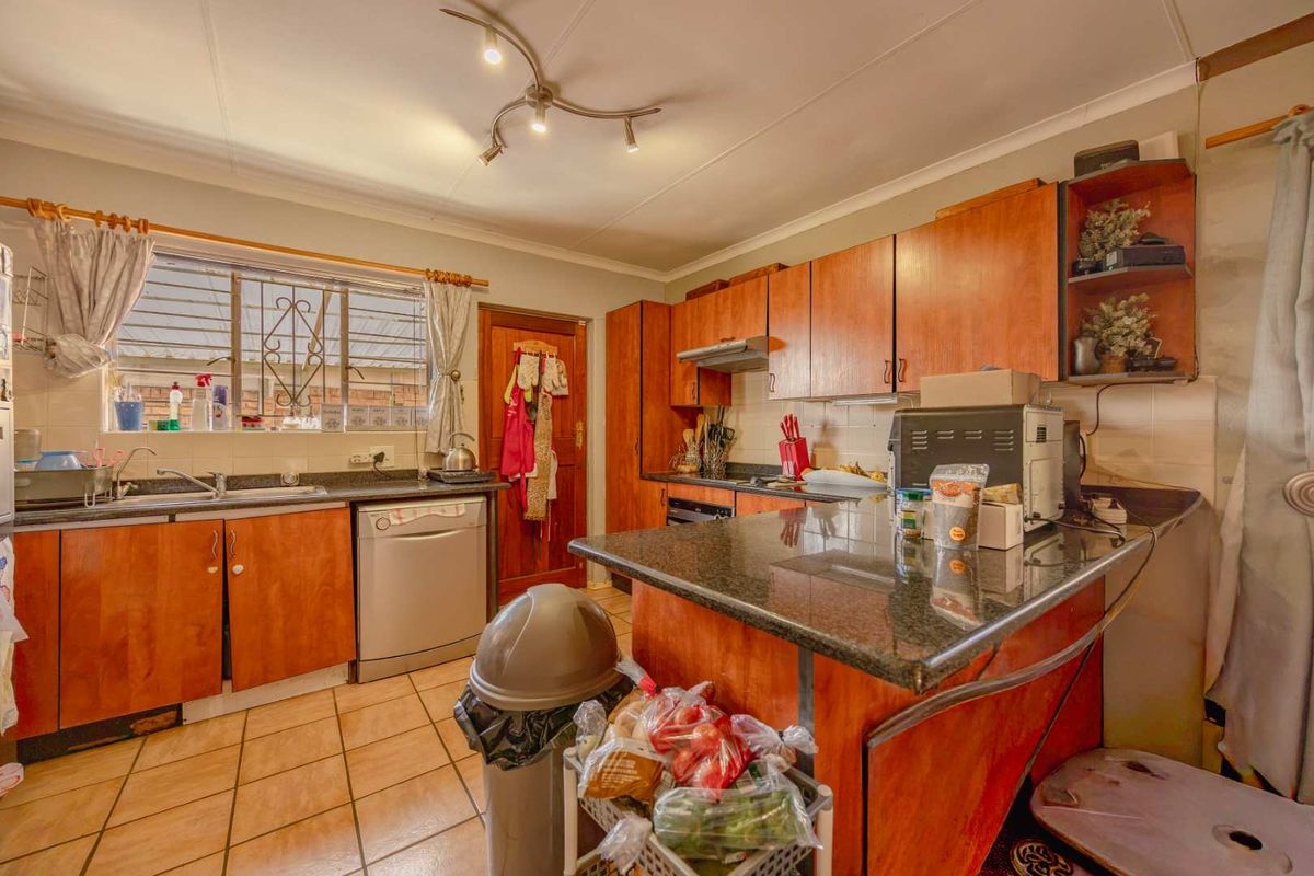 A functional kitchen featuring wooden cabinetry, granite countertops, tiled flooring, and a breakfast nook, offering a practical layout for daily meal preparation.