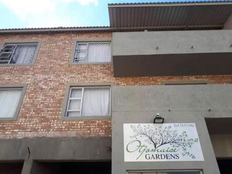 Front facade of Otjomuise Gardens townhouse complex featuring face brick construction, concrete balconies, and aluminium window frames.