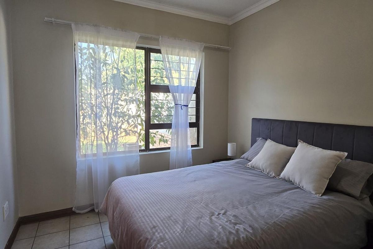 A functional bedroom featuring tiled flooring, a window with security bars, and a built-in cupboard.