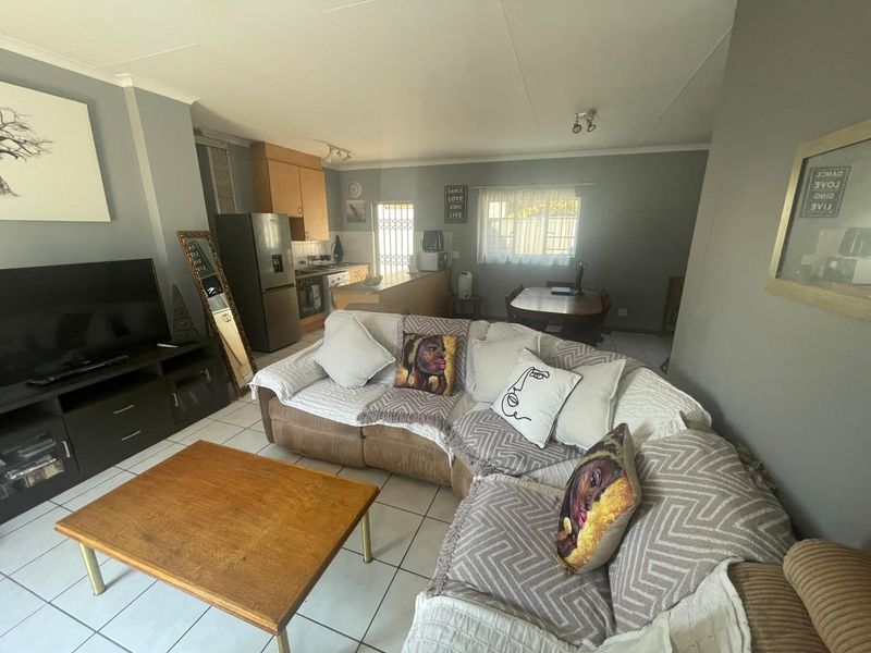 Open-plan living and dining area featuring tiled flooring and an integrated kitchen with built-in cabinetry and appliances.