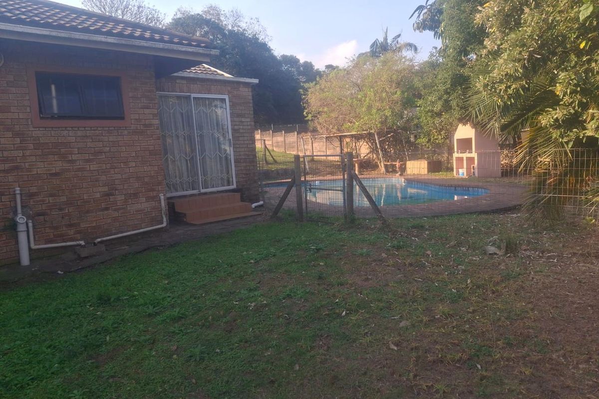 Rear view of the property featuring a brick facade, sliding door access, a swimming pool, and a built-in outdoor braai area.