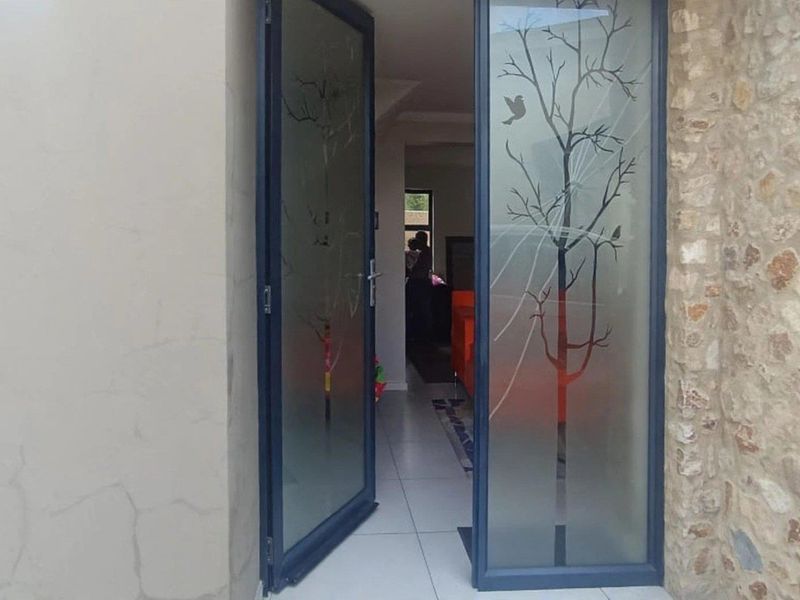 Entrance featuring decorative etched glass double doors, stone cladding accents, and tiled flooring leading into the main living area.