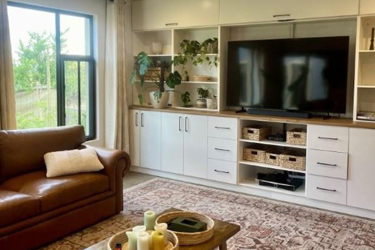 A well-maintained living room featuring extensive custom built-in cabinetry with integrated shelving and a large window providing natural light.