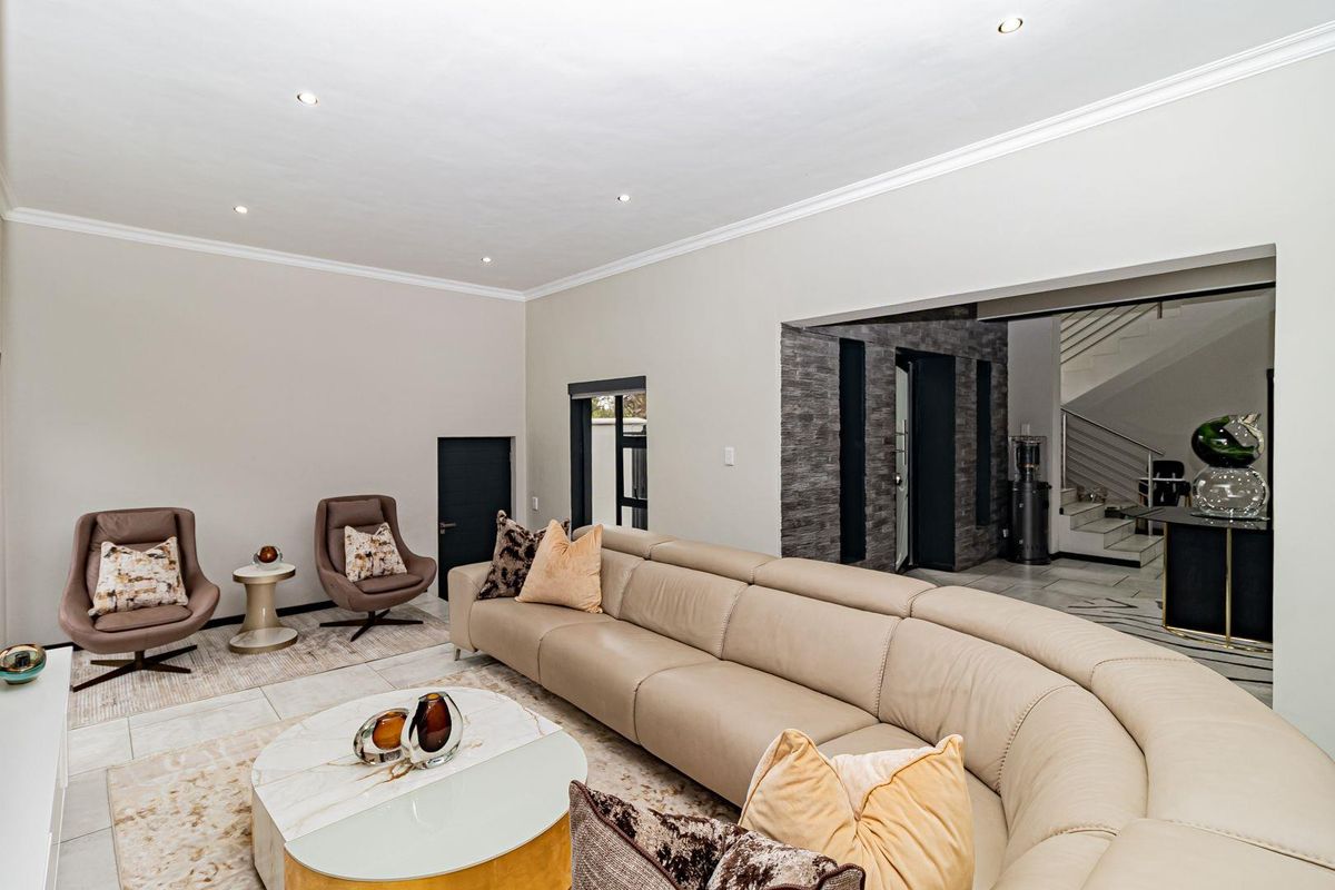 Spacious living room featuring tiled flooring, recessed downlighting, crown molding, and a decorative stone feature wall leading to an adjacent staircase area.