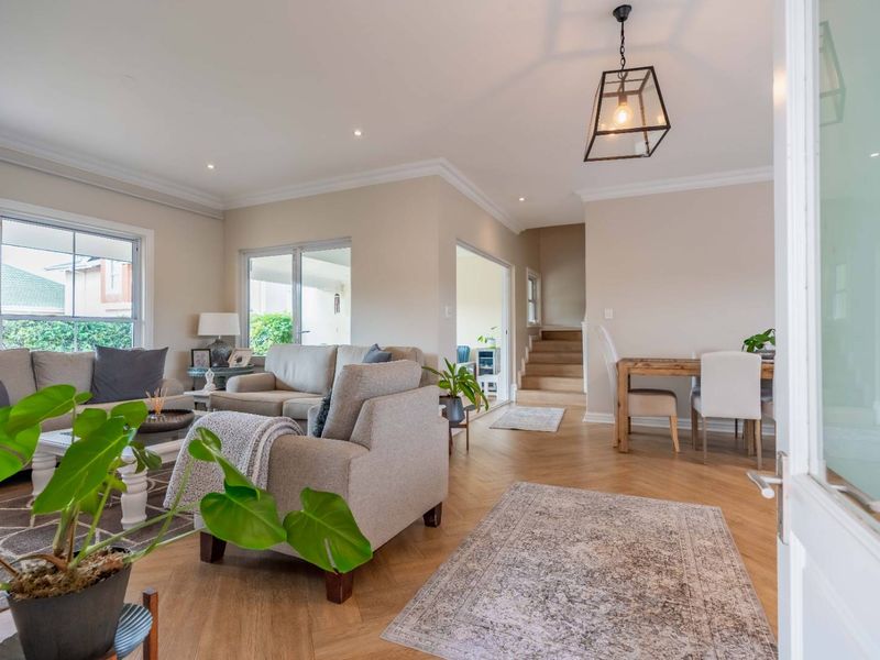 Bright open-plan living and dining area featuring elegant herringbone timber flooring, recessed lighting, and seamless access to outdoor spaces.