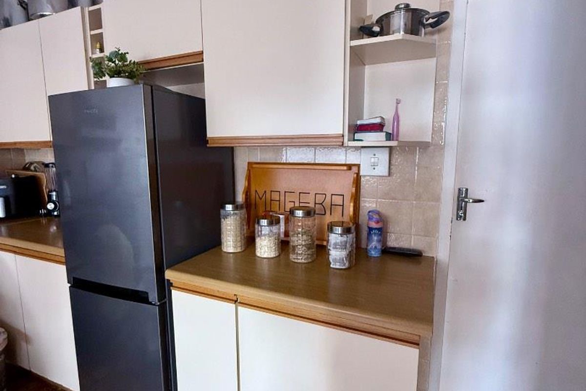A functional kitchen area featuring light-toned cabinetry, laminate countertops, and tiled flooring, providing a practical workspace for daily meal preparation.