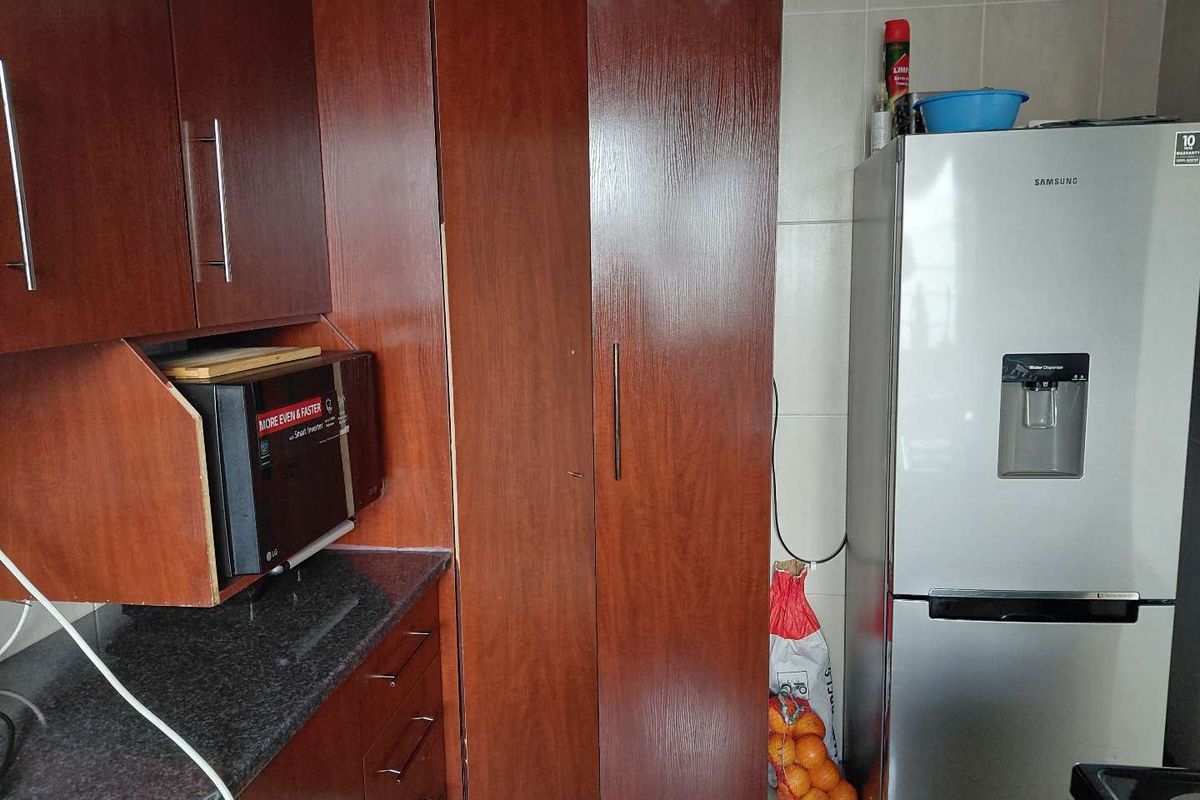 A functional kitchen area featuring dark wood-finish cabinetry, granite countertops, and a built-in microwave space, providing practical storage and preparation surfaces.
