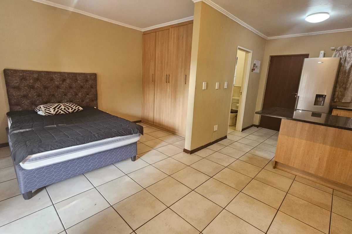 Open-plan studio apartment featuring tiled flooring, built-in bedroom cupboards, and a compact kitchen area with granite countertops.