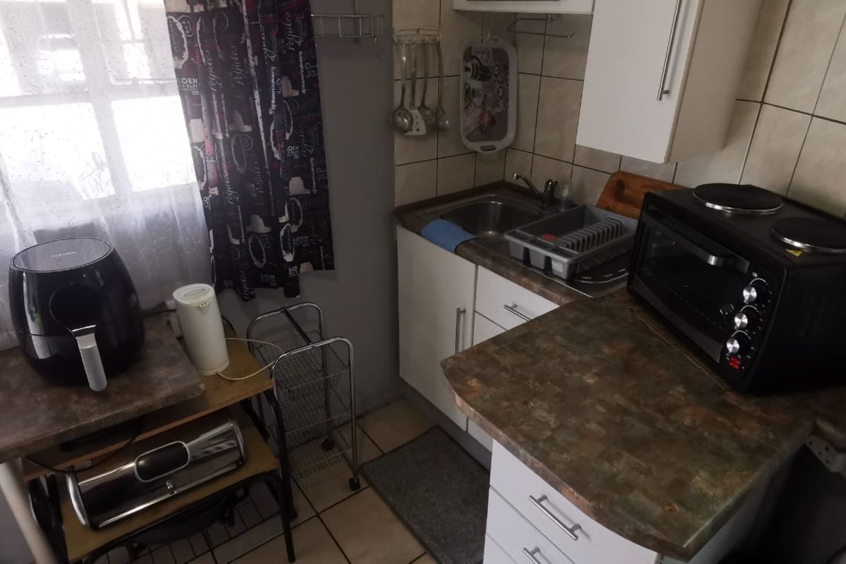 Compact kitchen featuring built-in cabinetry, laminate countertops, a stainless steel sink, and tiled backsplash, offering a functional prep area.