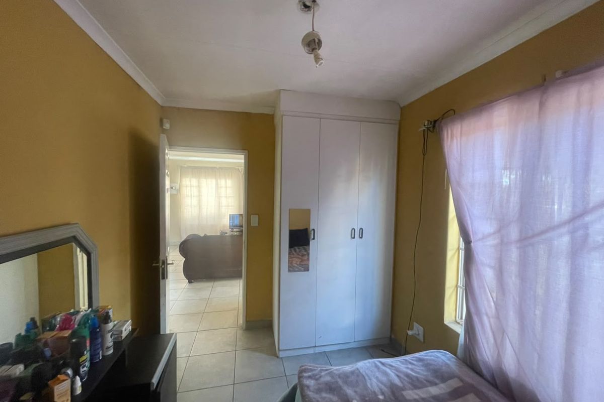 A bedroom featuring tiled flooring, a built-in wardrobe, and cove cornicing, with an adjacent view into the living area.
