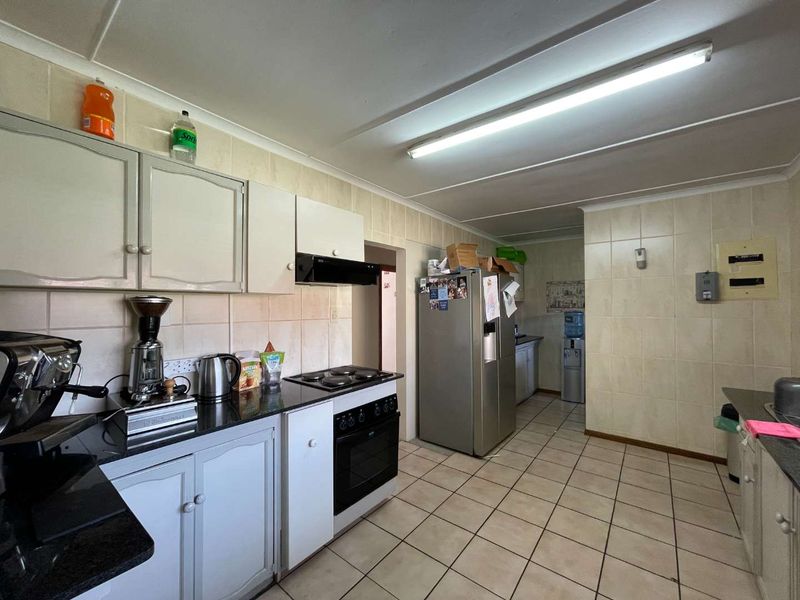 Functional kitchen featuring built-in cabinetry, granite countertops, electric stove with extractor fan, and tiled finishes throughout.