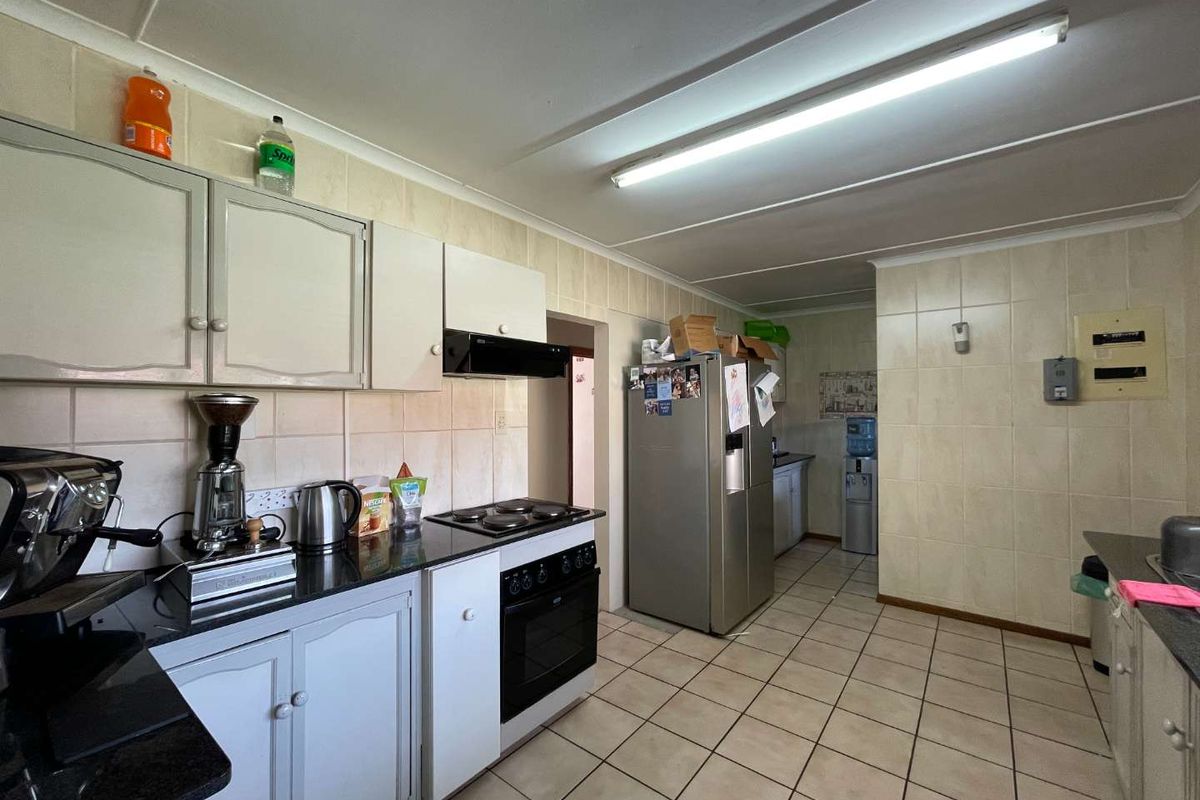 Functional kitchen featuring built-in cabinetry, granite countertops, electric stove with extractor fan, and tiled finishes throughout.