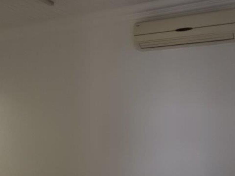 A clean, empty office space featuring a wall-mounted air conditioning unit and a classic beaded ceiling finish.