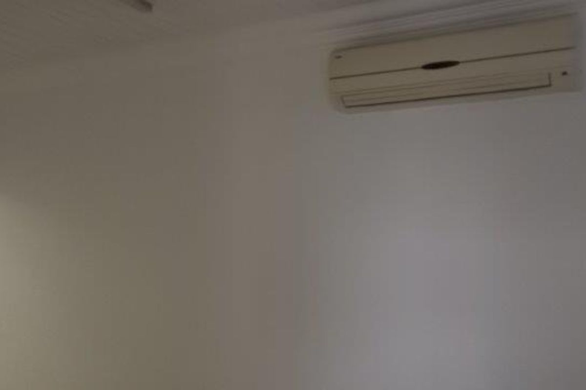A clean, empty office space featuring a wall-mounted air conditioning unit and a classic beaded ceiling finish.