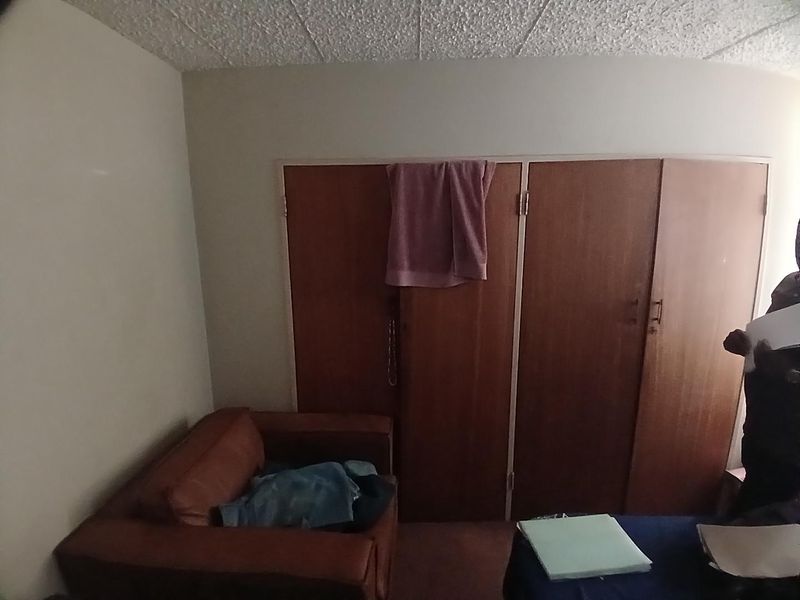 A bedroom featuring built-in wooden cupboards, showing signs of age and requiring cosmetic updates to improve the overall aesthetic.