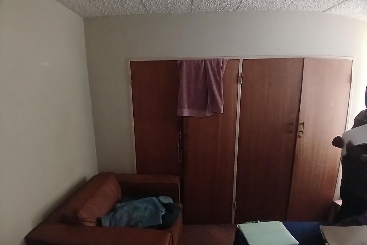 A bedroom featuring built-in wooden cupboards, showing signs of age and requiring cosmetic updates to improve the overall aesthetic.