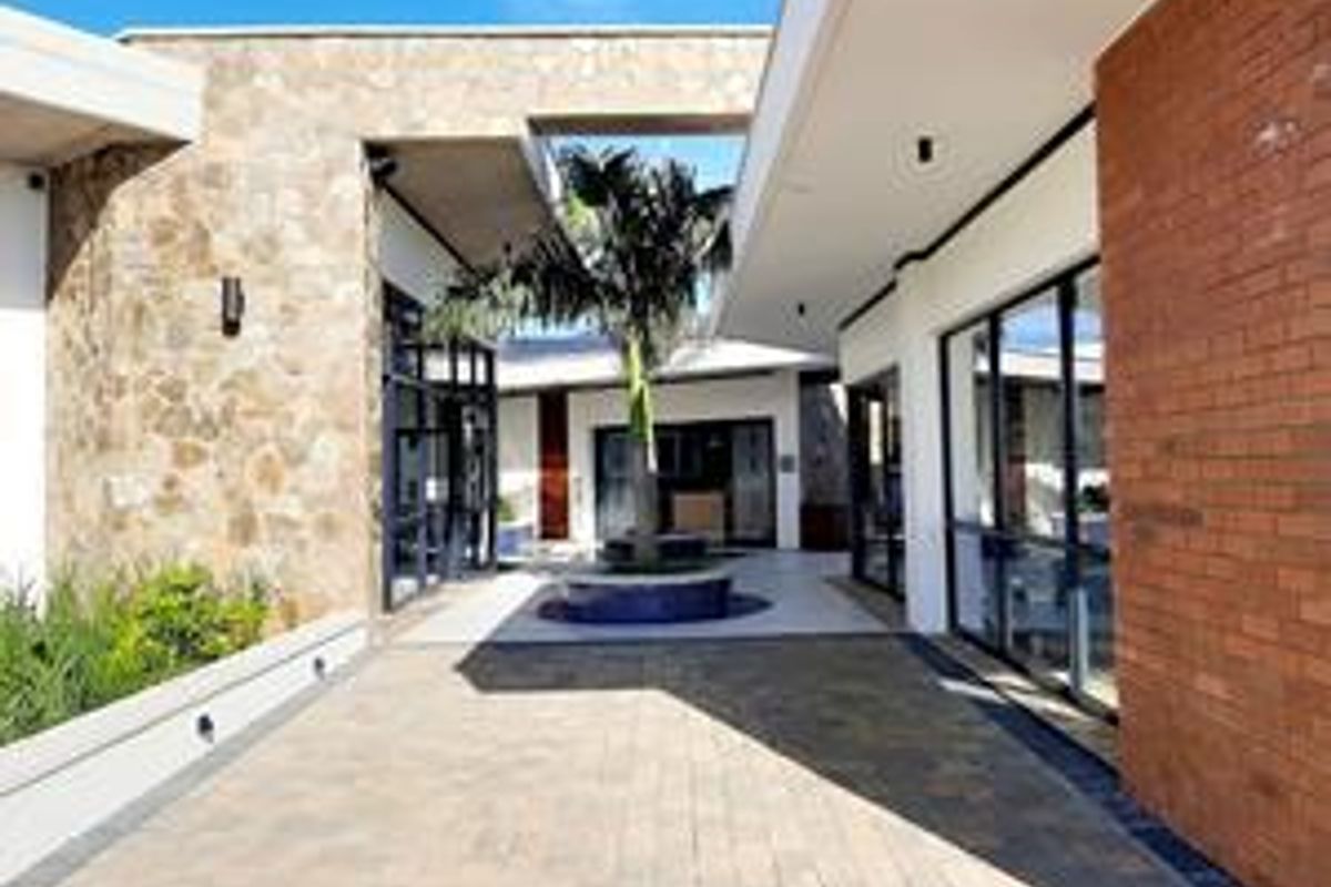 A modern, well-maintained courtyard featuring stone and brick architectural finishes, paved flooring, and a central landscaped planter area.