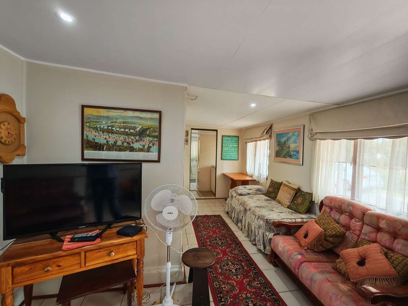 A functional living room featuring tiled flooring, recessed downlighting, and window blinds, providing a comfortable and practical space for relaxation.