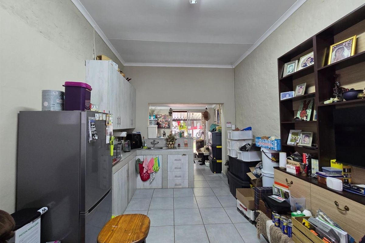 A functional kitchen area featuring built-in cabinetry, tiled flooring, and a pass-through window connecting to the adjacent living space.
