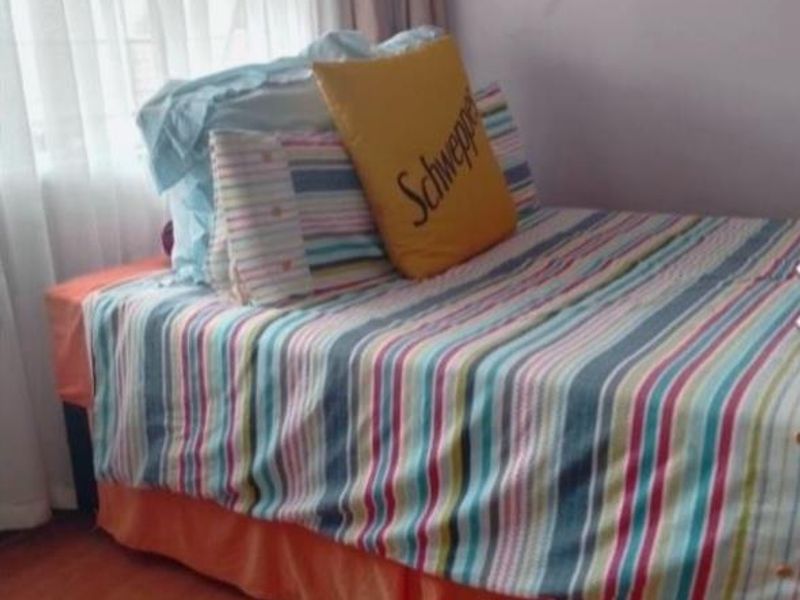 A bedroom featuring laminate flooring and window treatments, providing a functional space for rest.
