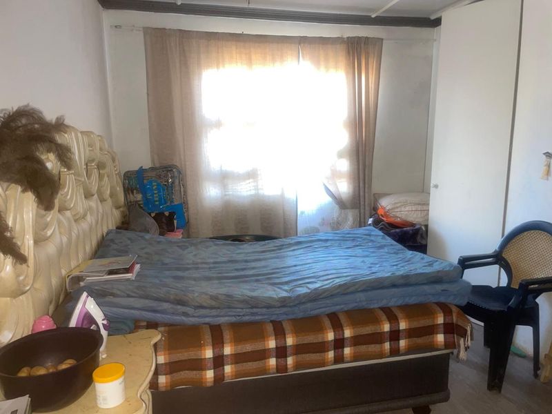 A bedroom featuring a built-in wardrobe and natural light from the window. The space requires cosmetic updates to improve its overall condition.