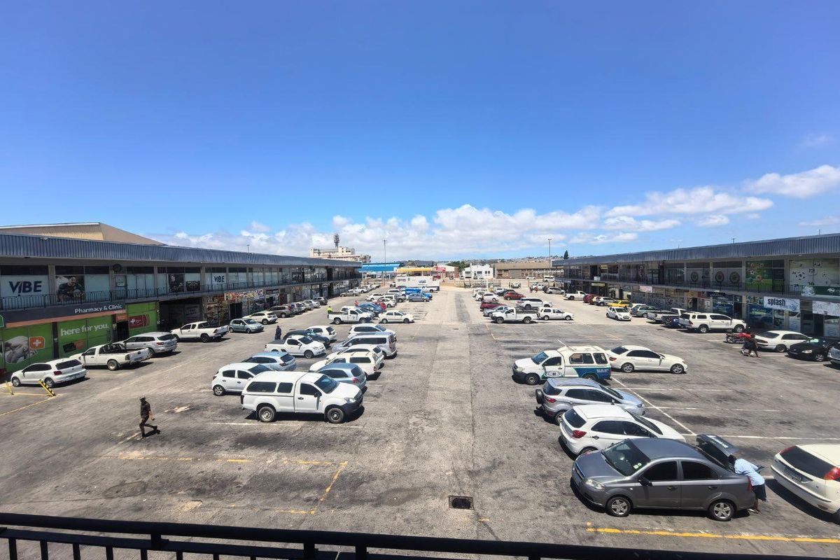Elevated view of a commercial shopping center parking lot with surrounding retail storefronts and ample parking space.