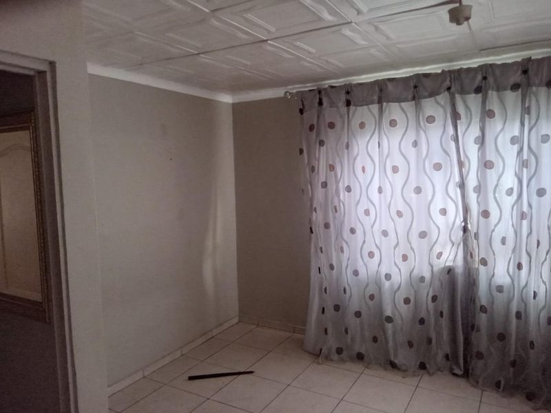 An empty bedroom featuring tiled flooring and a tiled ceiling, offering a blank canvas for potential renovation and interior design updates.