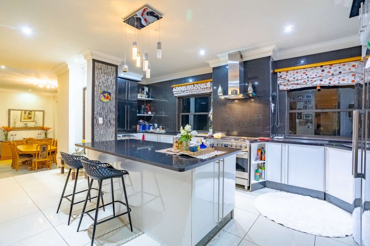 Modern kitchen featuring a central island with granite countertops, stainless steel gas stove, extractor fan, and elegant mosaic tile accents.
