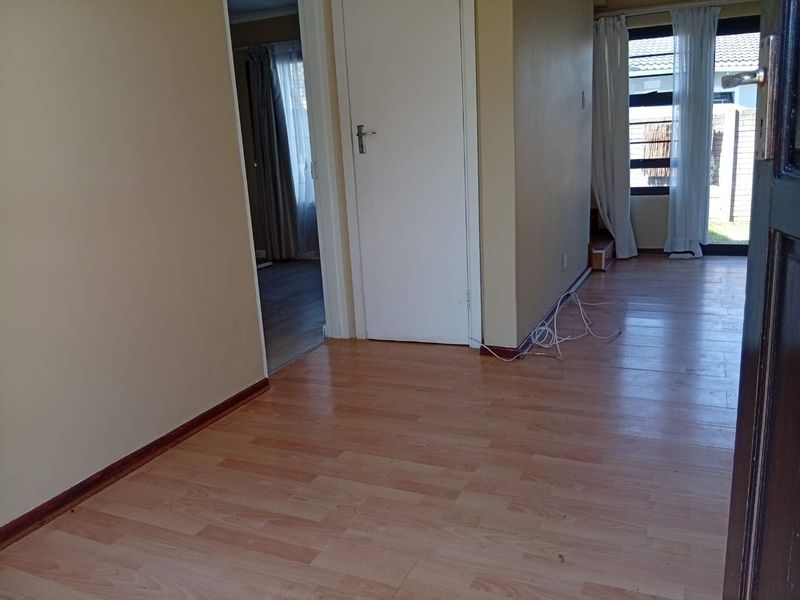 A vacant hallway featuring laminate flooring and access to adjacent rooms, providing a neutral foundation for interior design updates.